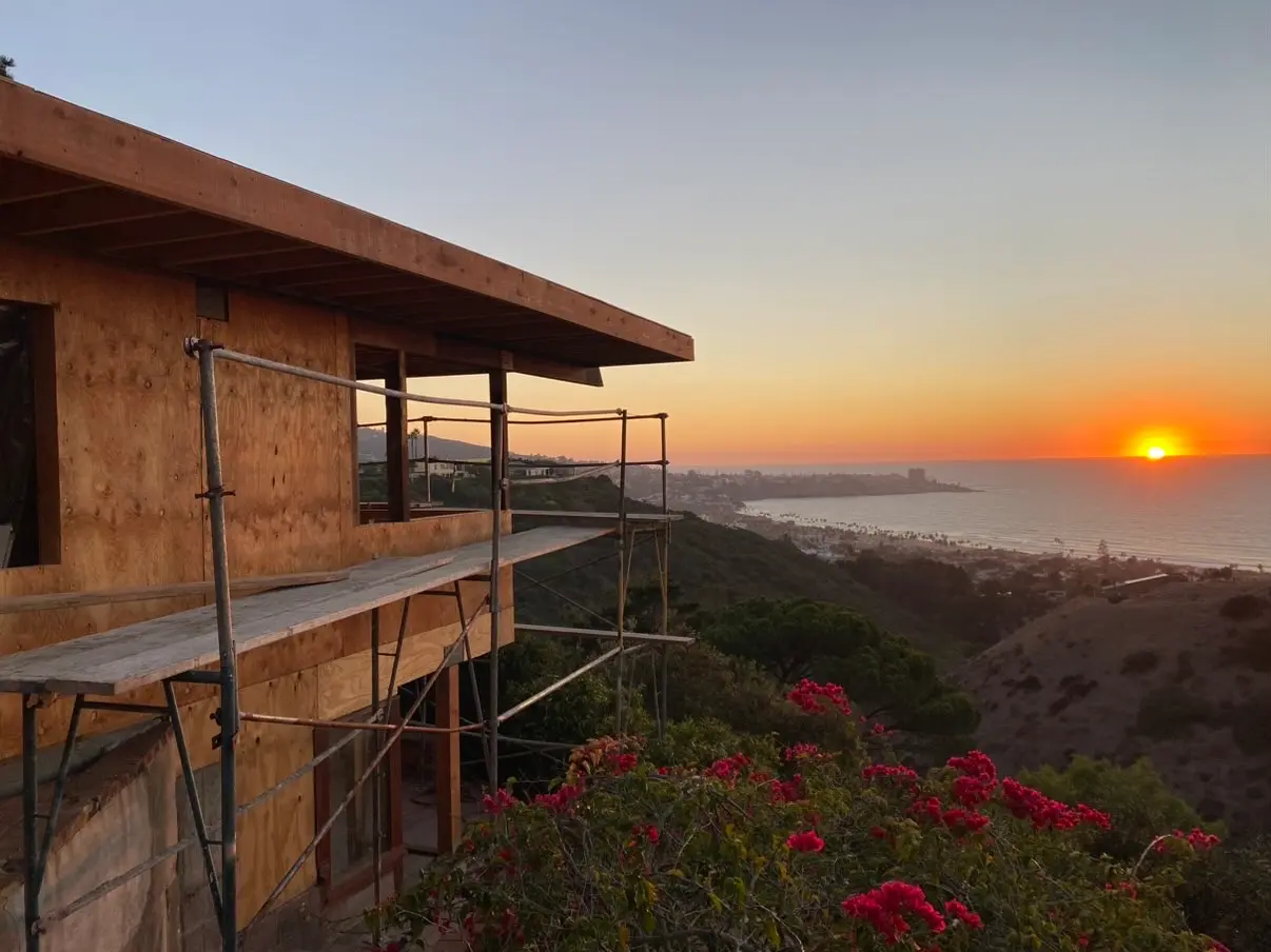 Hillside La Jolla home under construction at sunset with scaffolding and the Pacific on the horizon